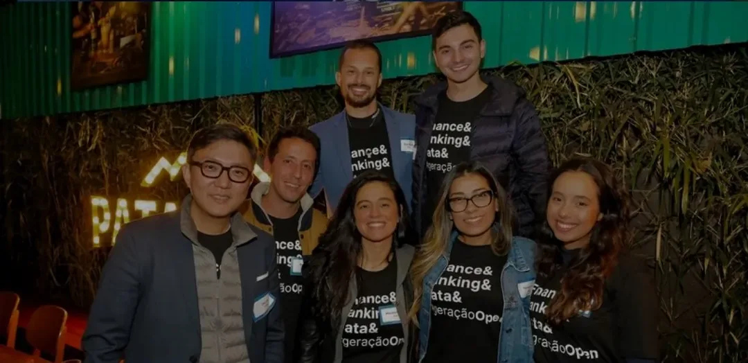 Mariana sorrindo com a equipe da startup de open finance num evento
